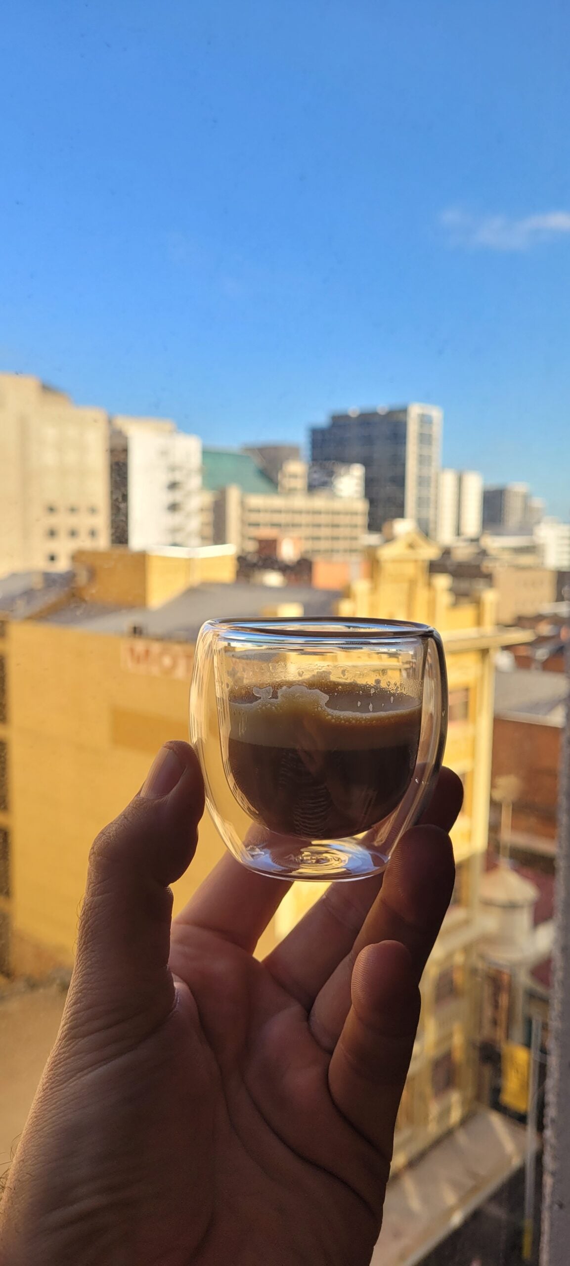 Holding a macchiato coffee and looking out the window from the YSL office.